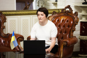 Iryna Sarancha sitter vid ett bord med en ukrainsk flagga bredvid sig.